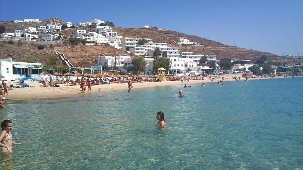 un groupe de personnes dans l'eau d'une plage dans l'établissement Mykonos Rooms, à Agios Stefanos