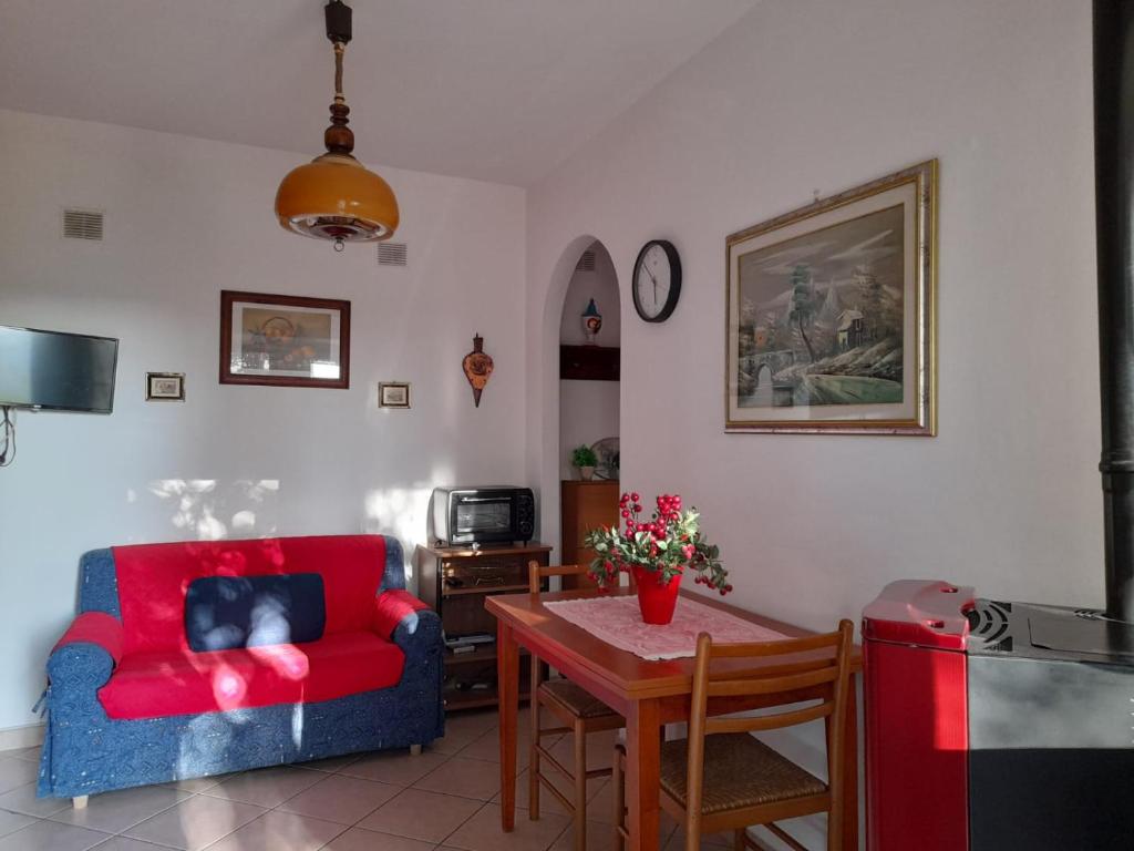 uma sala de estar com um sofá vermelho e uma mesa em 8380 Morellino little house em Montemerano