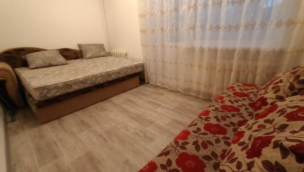 a small room with a bed and a curtain at 3-х комнатная квартира в Павлодаре in Pavlodar