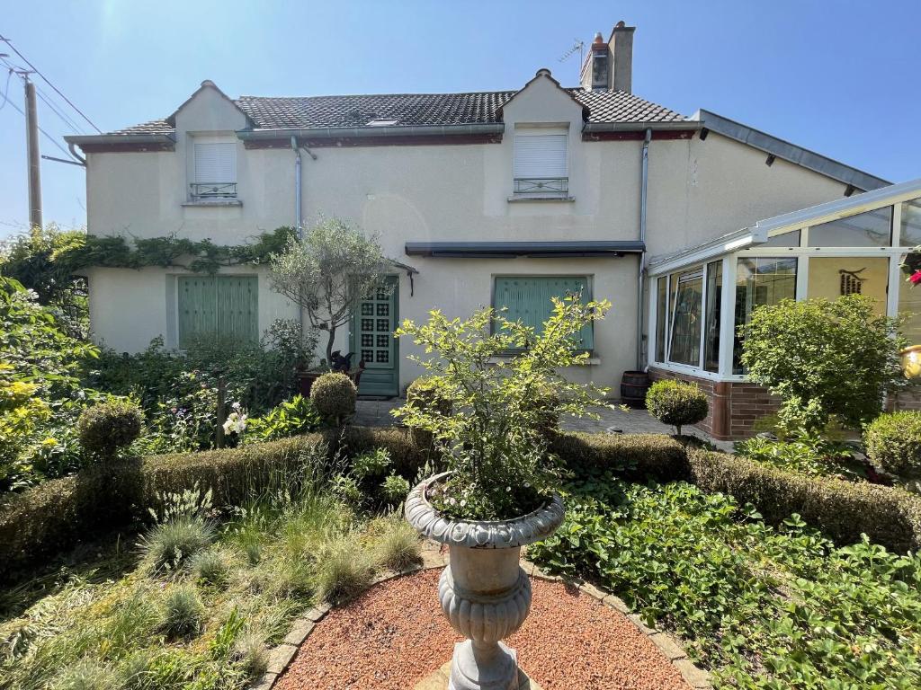 une maison avec une plante dans un vase dans la cour dans l'établissement La Maison d'Andrée, à Pluvet