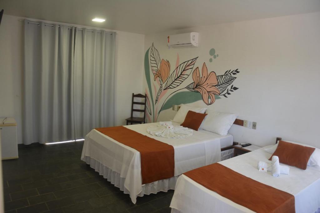 a bedroom with two beds and a mural on the wall at Hotel Brisa dos Abrolhos in Alcobaça