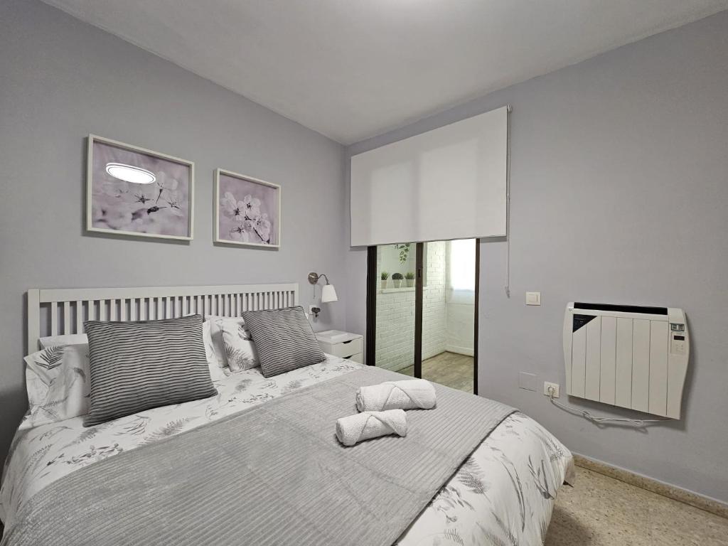 een slaapkamer met een groot bed en 2 handdoeken bij Vacacional Buyma - Parking privado -GRATUITO- in Málaga