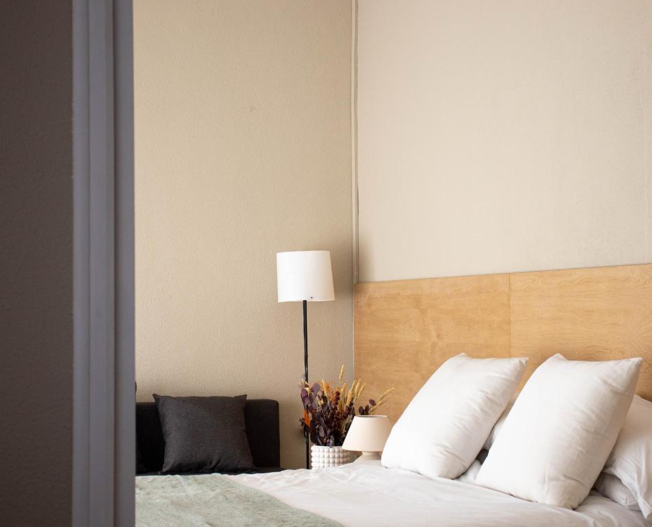 1 dormitorio con 1 cama con almohadas blancas y lámpara en Apartamentos Albacete, en Albacete