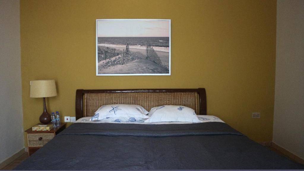a bed with two pillows and a picture on the wall at Cliffhaven Beach Resort Hotel in Accra