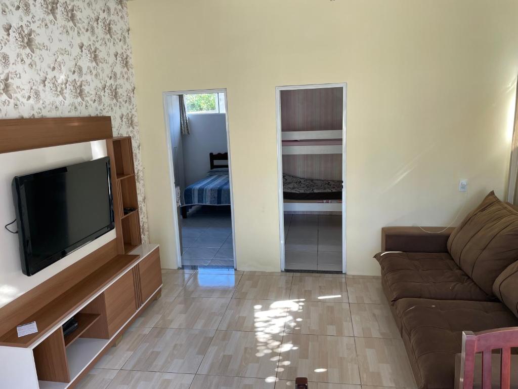 a living room with a couch and a flat screen tv at Casa praia do santinho in Florianópolis