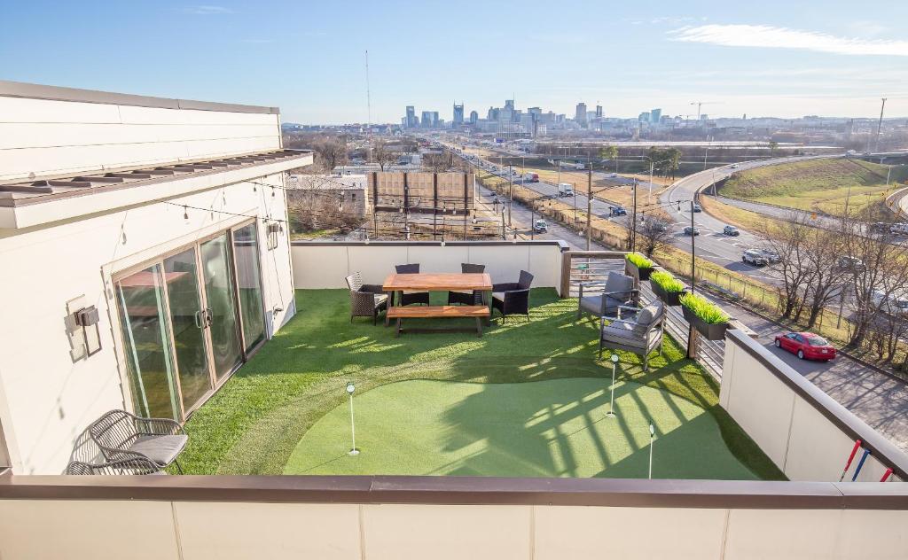 an apartment patio with a table and a green yard at Jack Daniels House with Rooftop Golf, City views! 8min to Whiskey Row! Sleeps 10! in Nashville
