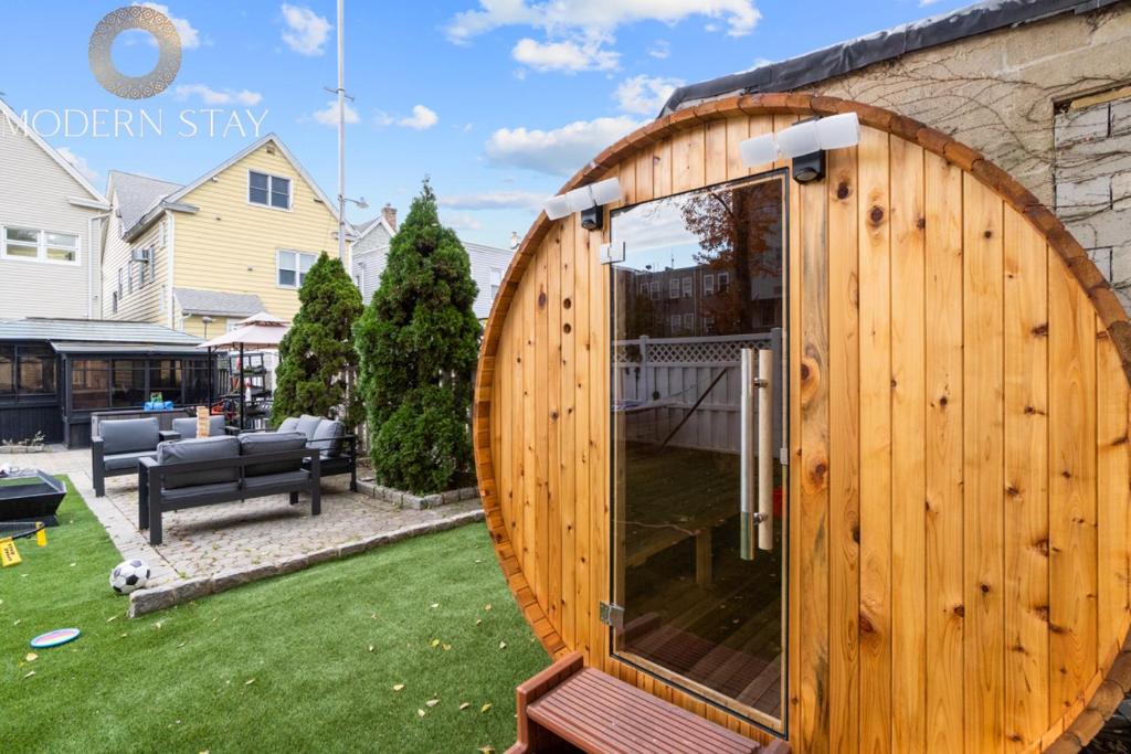 a wooden building with a large door in a yard at Epic Spa & Play Retreat NYC EWR Sleeps 30! in Bayonne