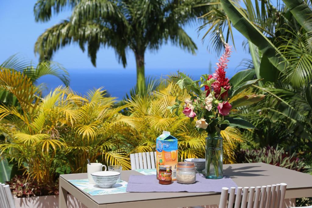 a table with a vase of flowers on it at Villa Ô Perchée in Pointe-Noire