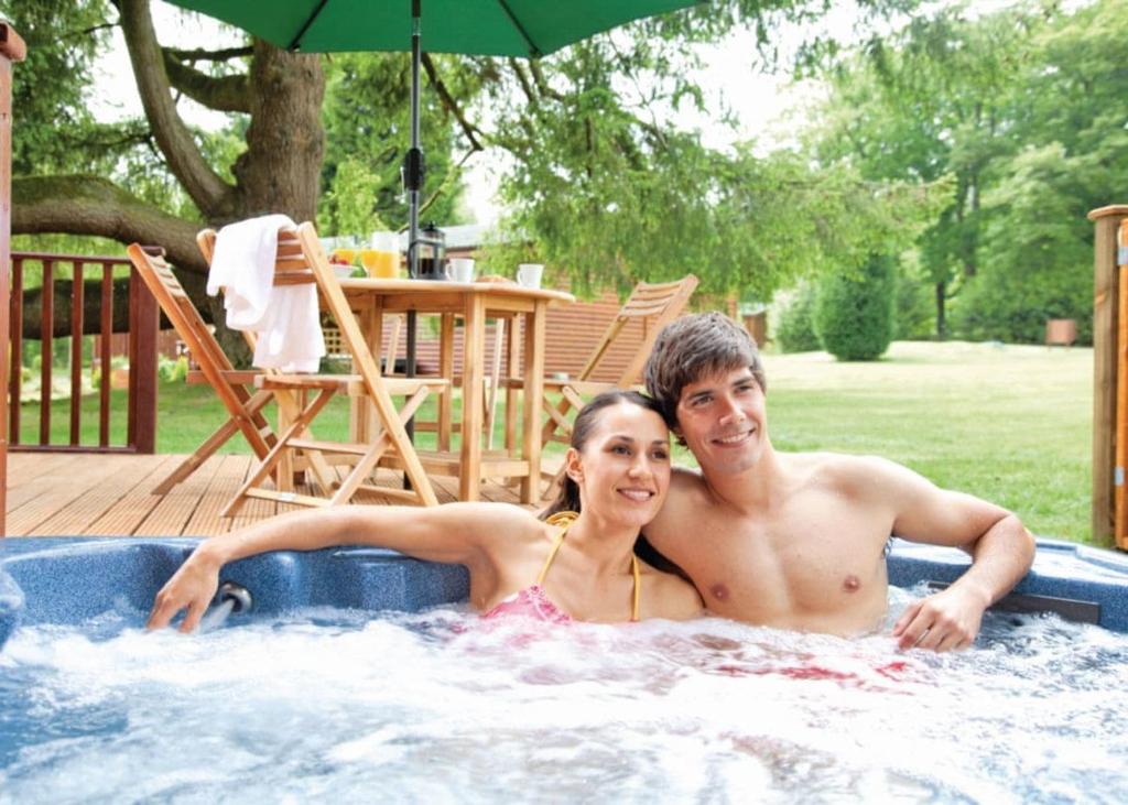 a man and a woman sitting in a hot tub at Ruby Country Lodges in Beaworthy