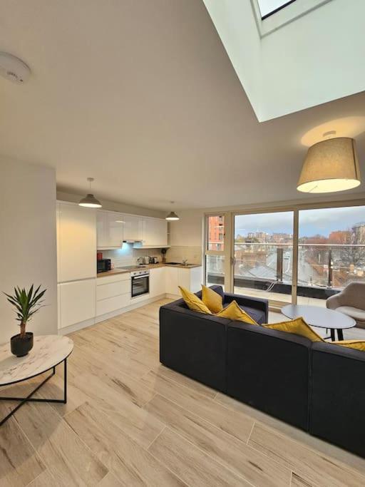 a living room with a black couch and a kitchen at Spacious and cosy house in Dublin