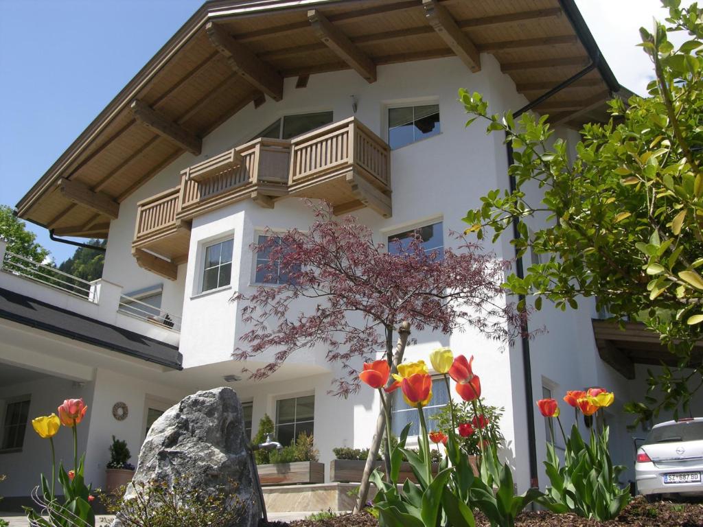 ein weißes Haus mit einem Balkon und Blumen in der Unterkunft Apart Ahorn in Finkenberg