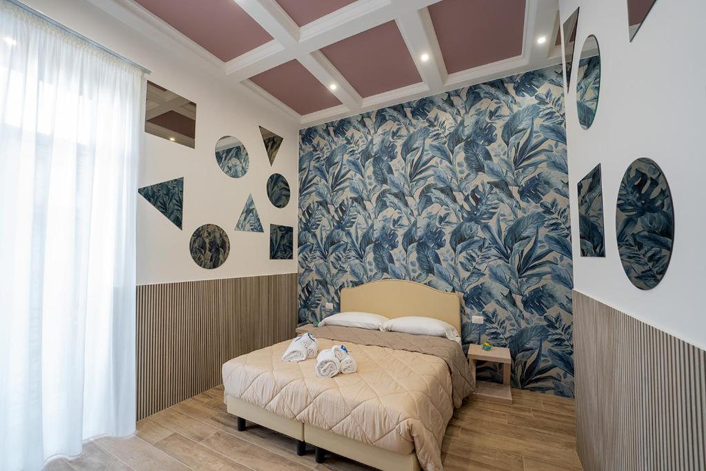 um quarto com uma cama e um papel de parede azul e branco em PC Boutique H Napoli Centro, by ClaPa Group em Nápoles