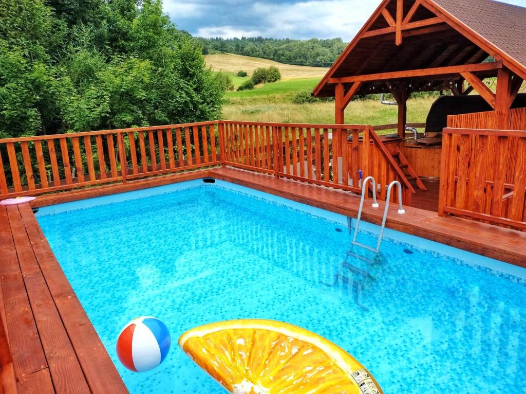a swimming pool on a wooden deck with a swimming pool at Całoroczne Domki Wypoczynkowe - Osada pod Górą in Ustrzyki Dolne