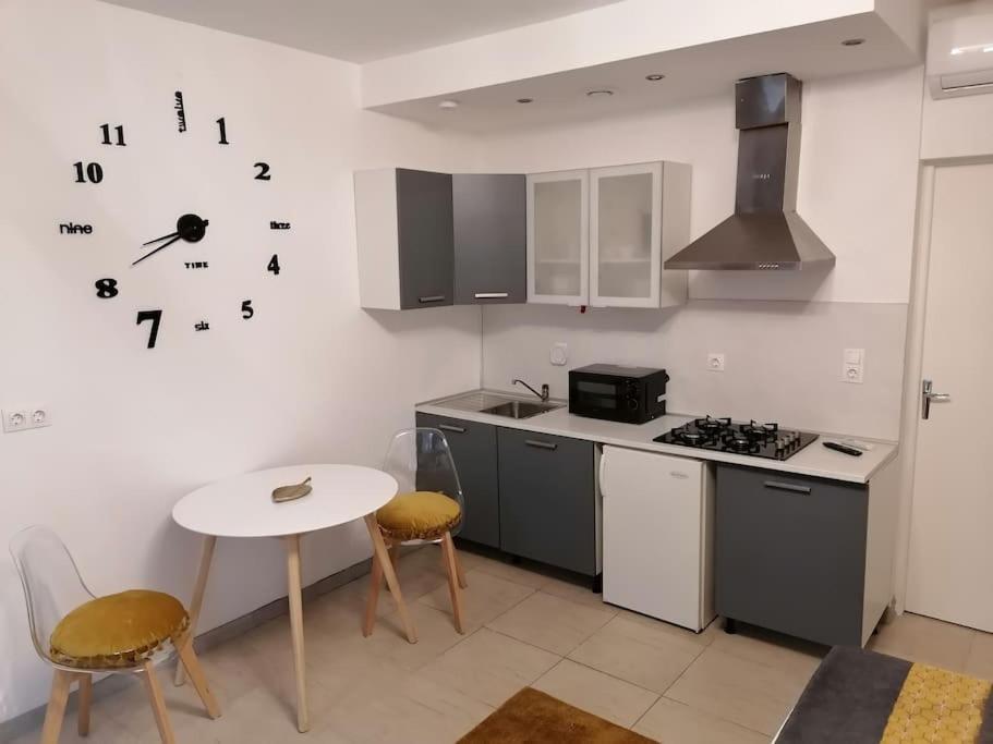 eine Küche mit einem Tisch, einem Herd und einer Uhr an der Wand in der Unterkunft Studio proche du centre-ville in Carcassonne