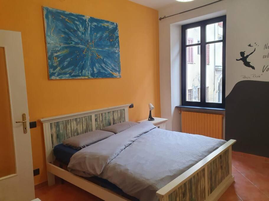 1 dormitorio con 1 cama con una pintura en la pared en Nel Cuore Pulsante della Città!, en Alessandria