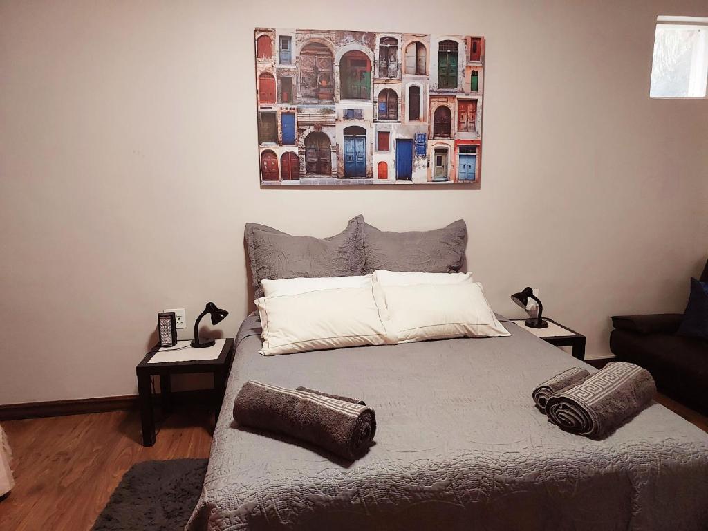 a bed in a bedroom with a painting on the wall at Adorable Designs in Pretoria