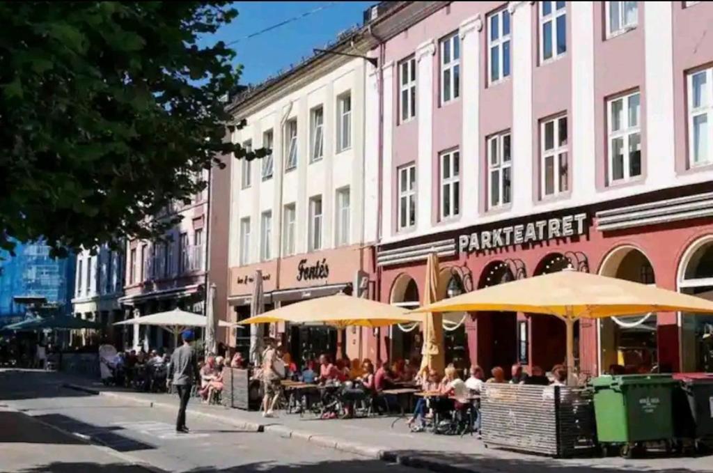 un grupo de personas sentadas en mesas bajo sombrillas en una calle en Central Grünerløkka, close to city center, en Oslo