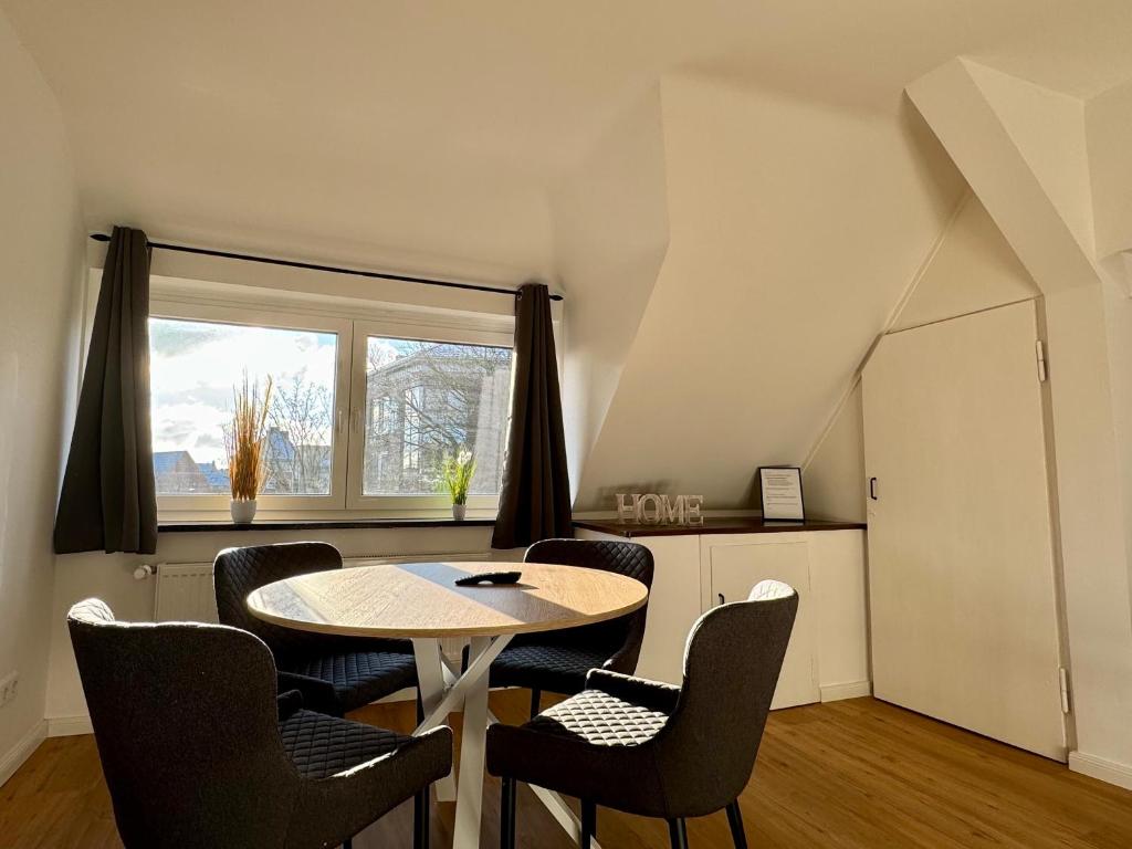 a room with a table and chairs and a window at Modernes City Apartment nahe Hbf in Emden