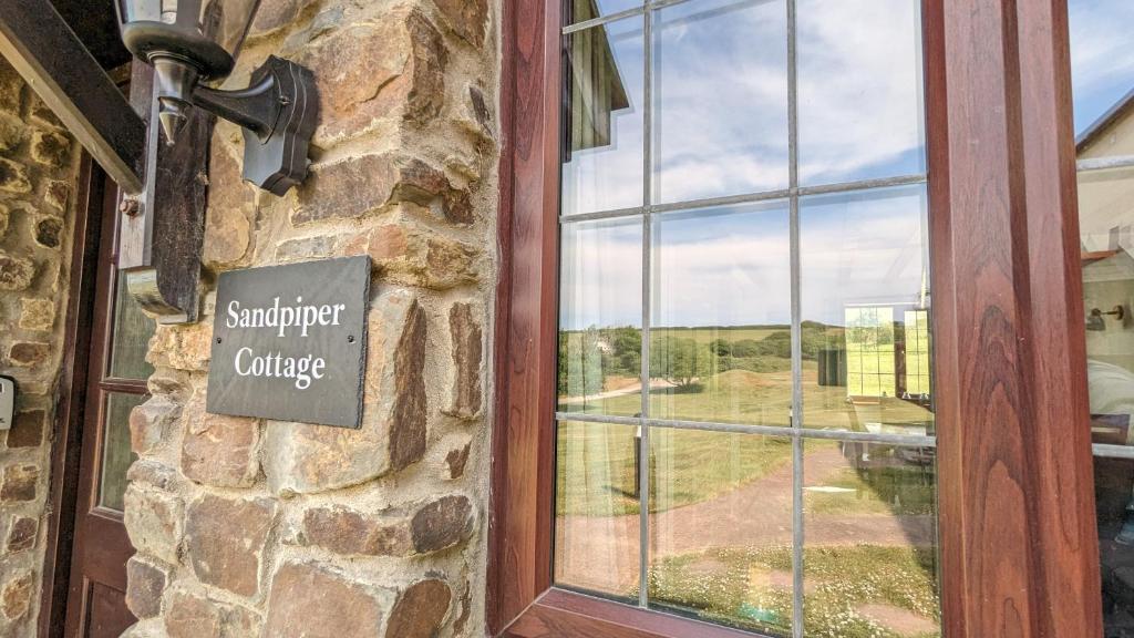 ein Schild an der Seite eines Gebäudes mit Fenster in der Unterkunft Sandpiper Cottage: cosy home near the beach in Woolacombe