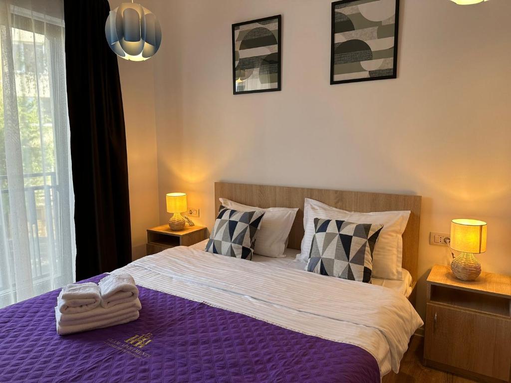 Lipatti 15 Apartments by GLAM LUXURY في تيميشوارا: غرفة نوم بسرير ارجواني مع مصباحين