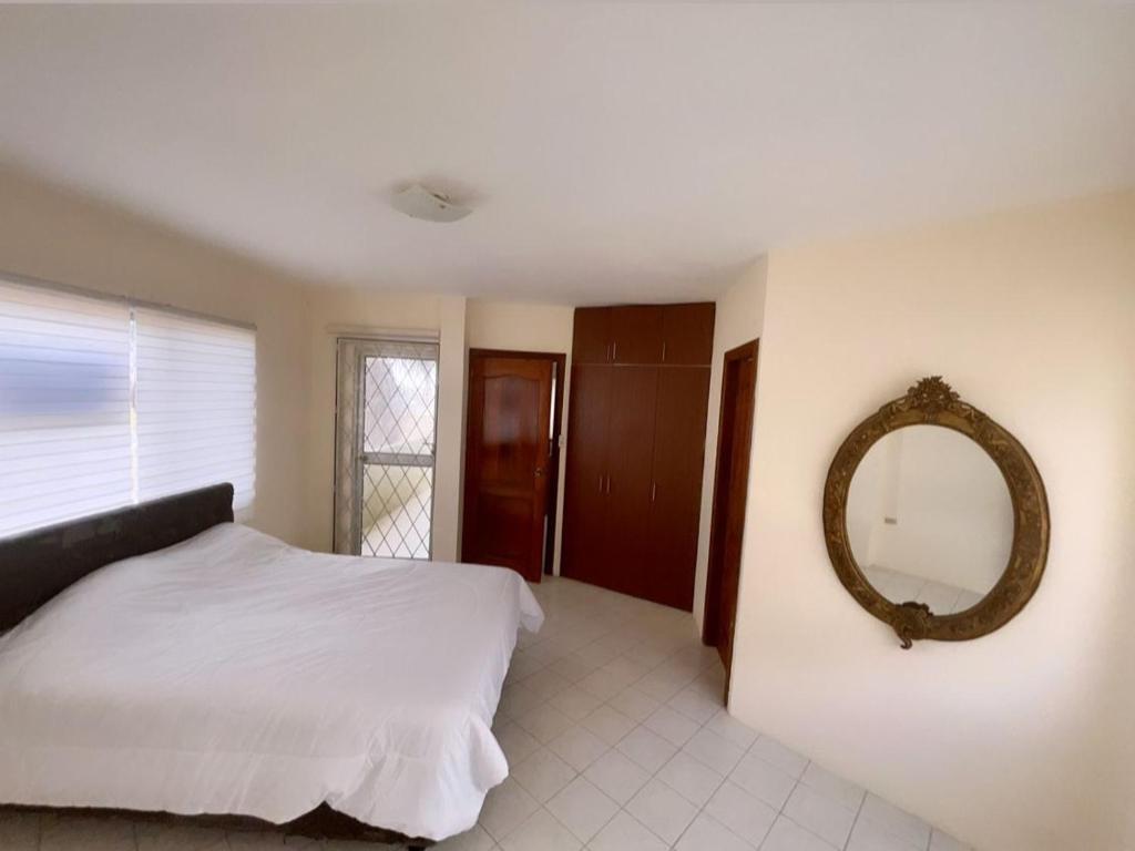 1 dormitorio con cama y espejo en la pared en Suites- Salinas, en Salinas