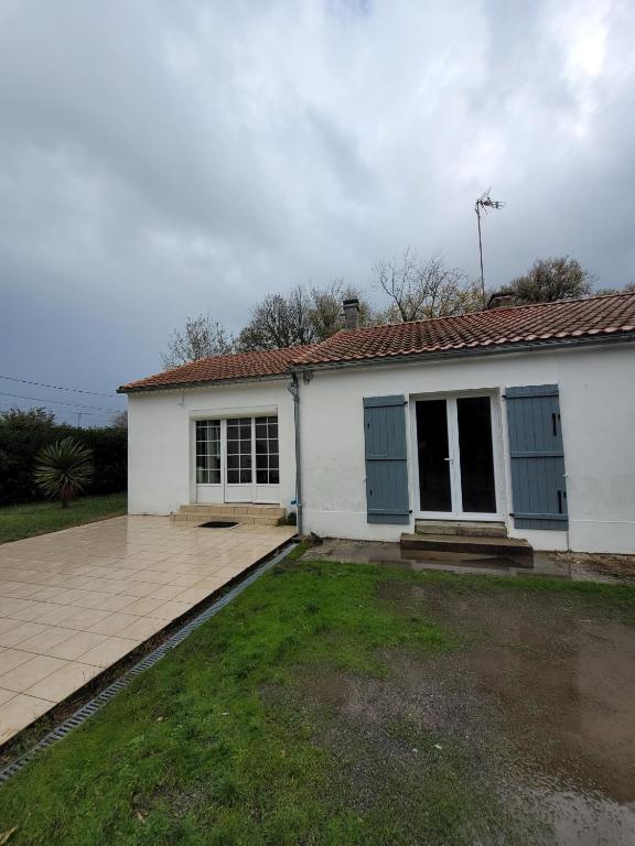 une maison blanche avec des portes bleues et une cour dans l'établissement Charmante Maison - Evasion nature et confort, à Saint-Jean-de-Monts