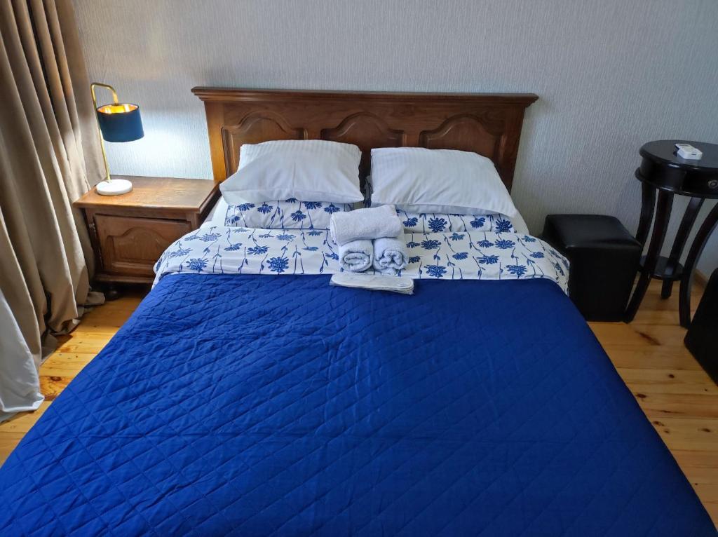 Friendly Guest House في كوتايسي: غرفة نوم بسرير ازرق عليها مناشف