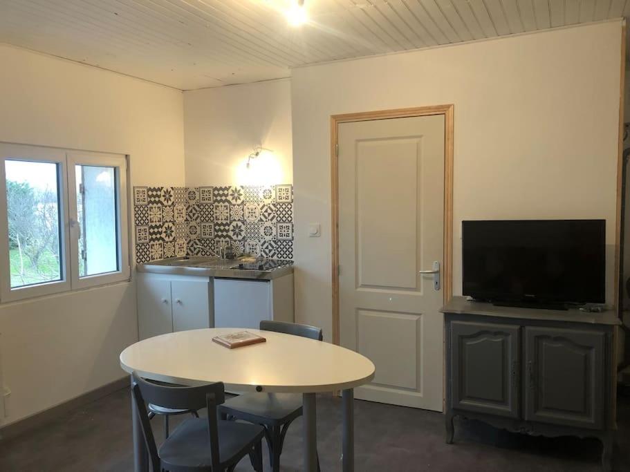 een kamer met een tafel en een televisie en een tafel en stoelen bij Studio des champs in Montélimar