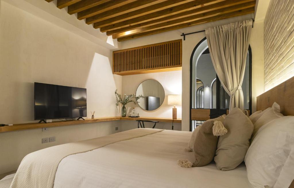 サンミゲル・デ・アジェンデにあるCasas y Suites Indigo San Miguelのベッドルーム(白い大型ベッド1台、薄型テレビ付)
