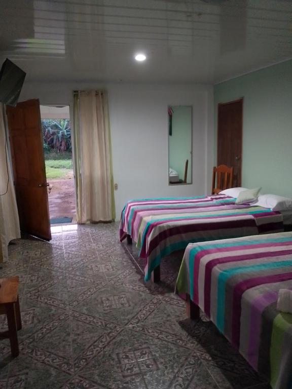 um quarto de hotel com três camas e uma porta em Habitacion en Bijagua em Bijagua