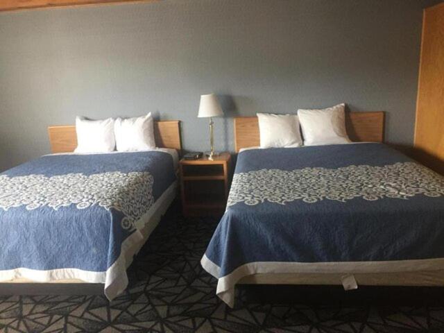 a hotel room with two beds and a lamp at Tomahawk Motor Lodge in Riverton