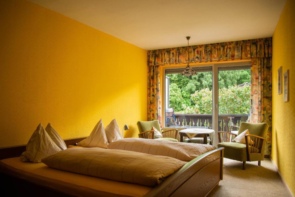 2 Betten in einem gelben Zimmer mit Fenster in der Unterkunft Gasthaus zum Odenwald 