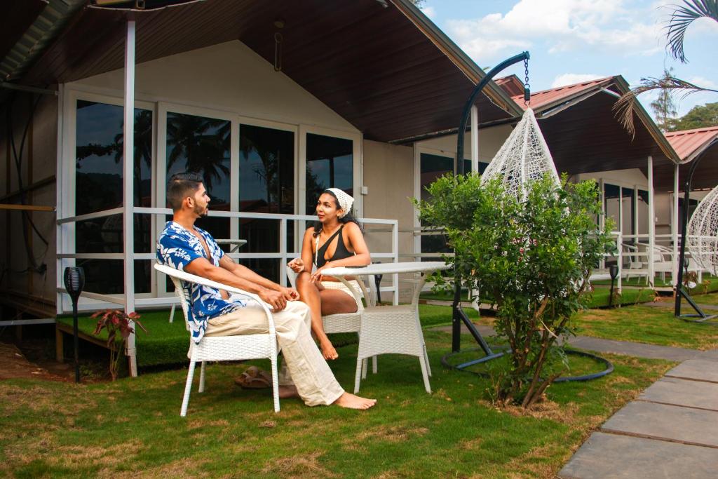 Ein Mann und eine Frau sitzen an einem Tisch vor einem Haus in der Unterkunft Luxurious Beach Resort Agonda in Agonda