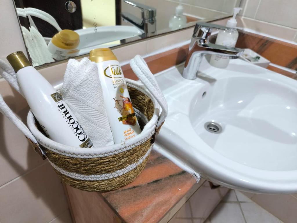 a bathroom with a basket with toothbrushes and a sink at Smart Home Vacation Home in Sharjah