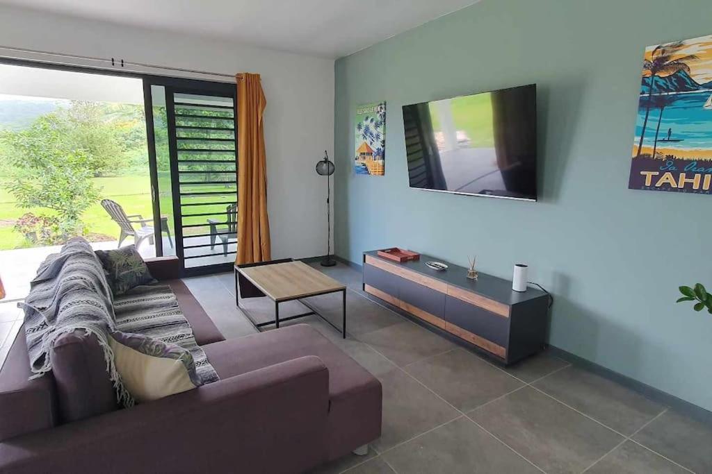uma sala de estar com um sofá e uma televisão de ecrã plano em Le Fare APE TARUA em Taputapuapea