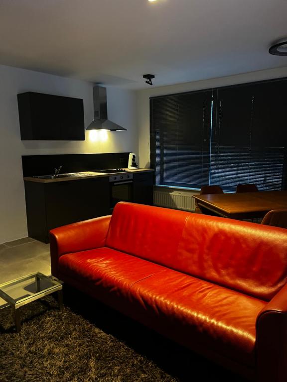 um sofá vermelho numa sala de estar com uma cozinha em Budget Flex em Geel