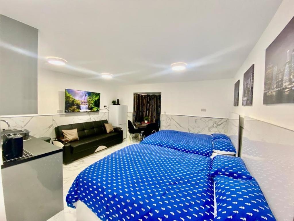 Cette chambre comprend un grand lit bleu et un canapé. dans l'établissement THE ROYAL BOUTIQUE STUDIO by LONDON SLEEP 6, à Hayes
