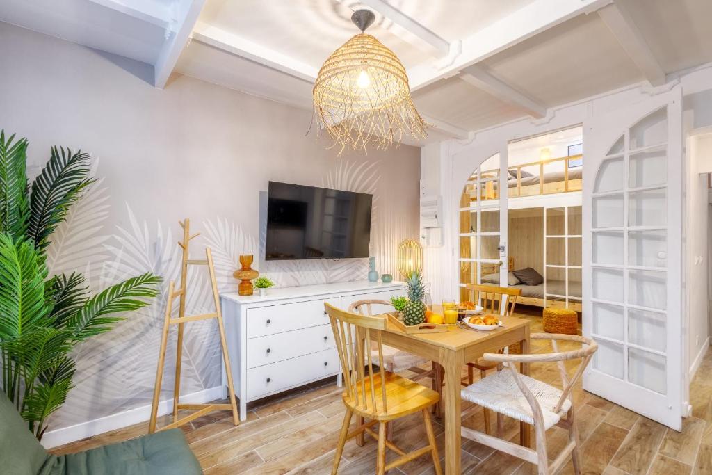 uma sala de jantar com uma mesa e uma televisão em Joyful tiny house seaside em Cabourg