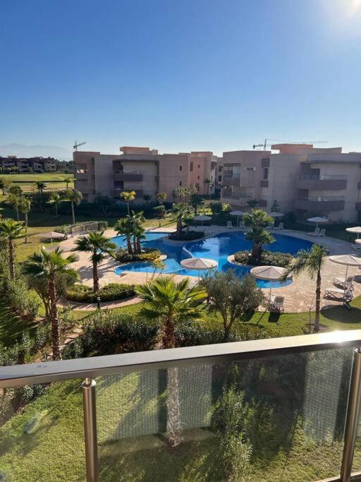 uitzicht op een zwembad met palmbomen en gebouwen bij Beautiful apartment in Golf City Marrakech in Marrakesh