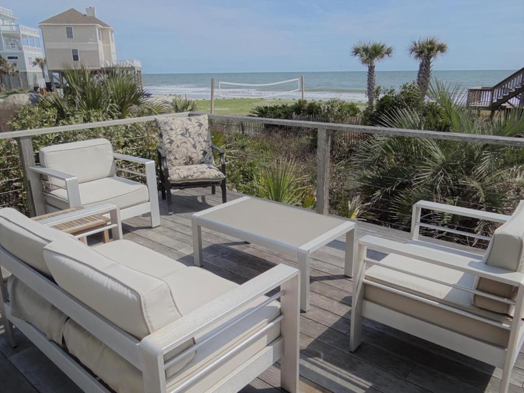 una terraza con sillas y mesas blancas y la playa en NorthStar, en Folly Beach