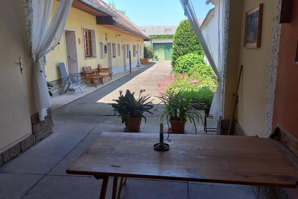 a wooden table in a courtyard with potted plants at Bauernhaus mit großem Innenhof und Garten in Seefeld-Kadolz