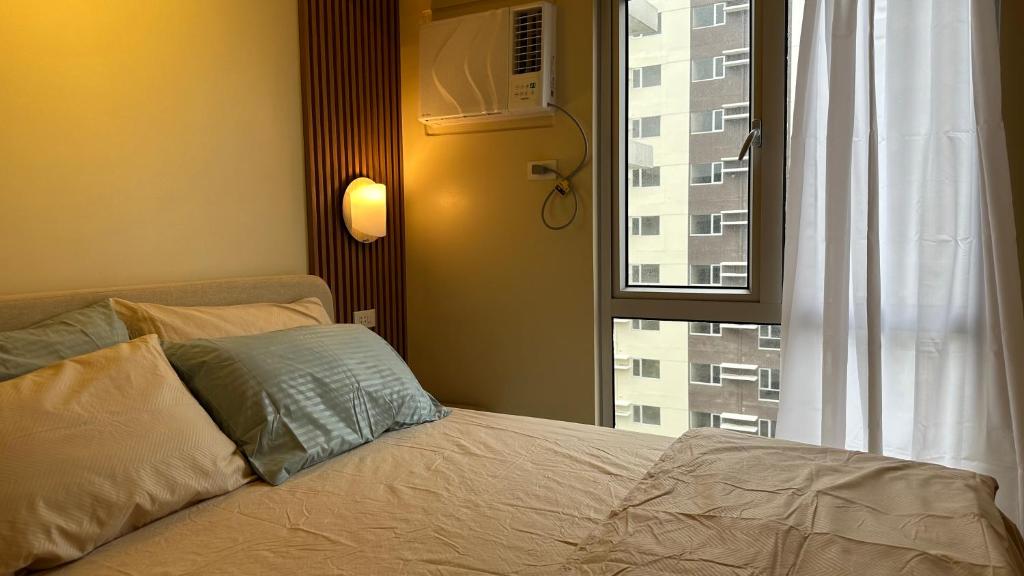 a bedroom with a bed and a window with a building at Iloilo Travellers Zen Zone in Iloilo City