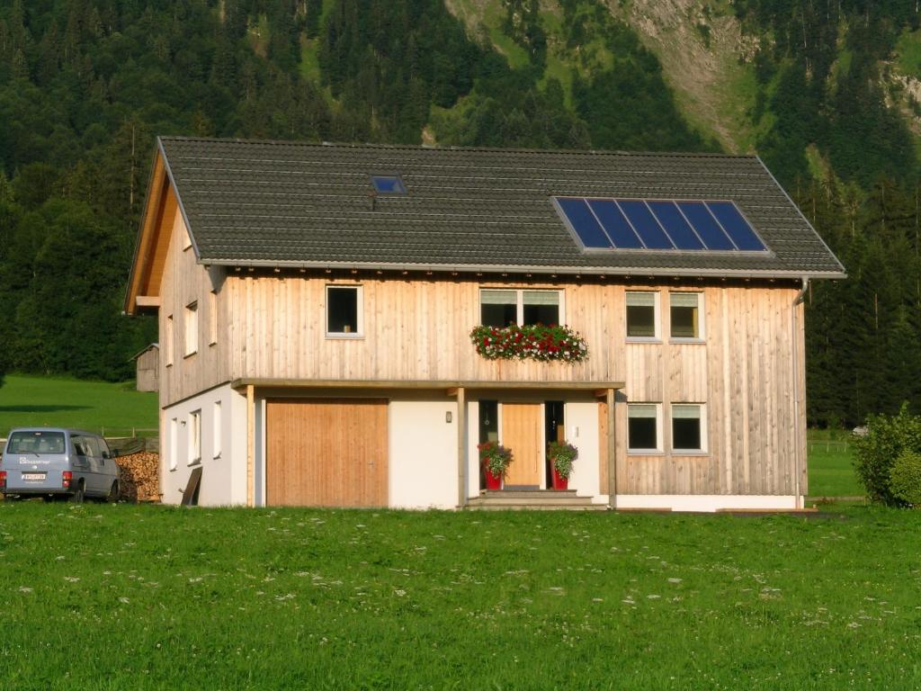 ein Haus mit einem Solardach und einer Garage in der Unterkunft Appartement Moosbrugger Haus Elisabeth in Schoppernau