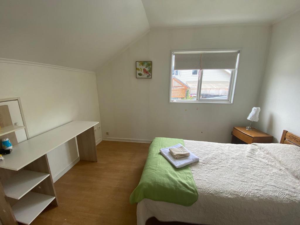 1 dormitorio con cama, escritorio y ventana en Cómoda casa para familias y/o amigos en Coihaique