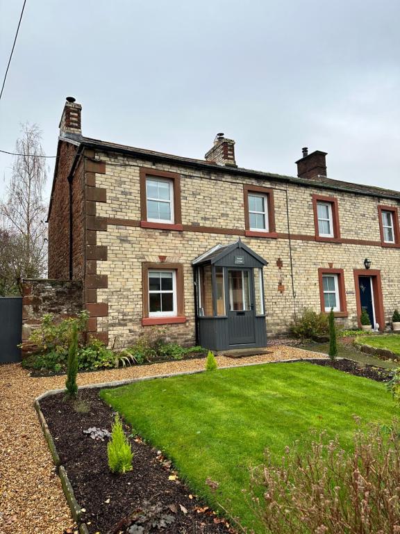 a brick house with a lawn in front of it at Luxury Cumbrian Cottage in Long Marton