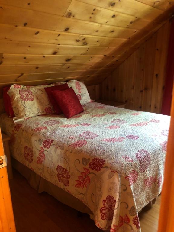 Cama en habitación con techo de madera en Le chalet du Golf à Rimouski, en Rimouski