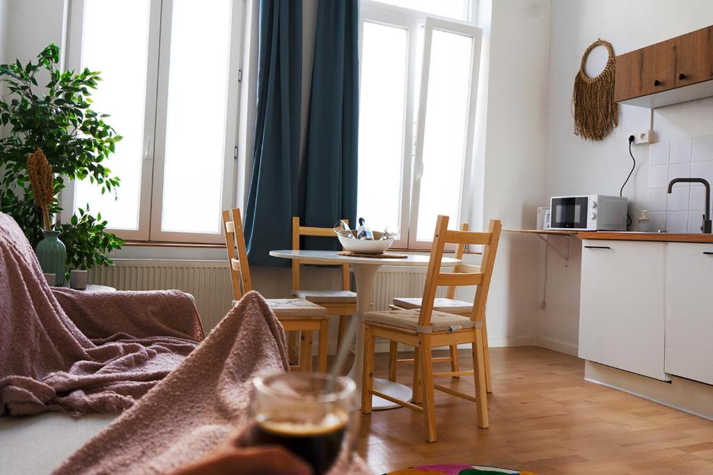 ein Wohnzimmer mit einem Tisch und Stühlen sowie eine Küche in der Unterkunft Le P'tit Bijou - Centre de Liège in Lüttich