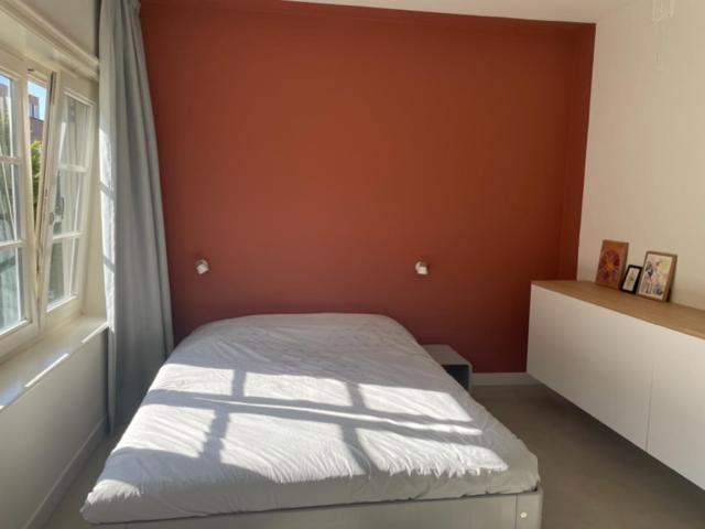 una camera da letto con un letto con una parete arancione e una finestra di Terra City West ad Amsterdam