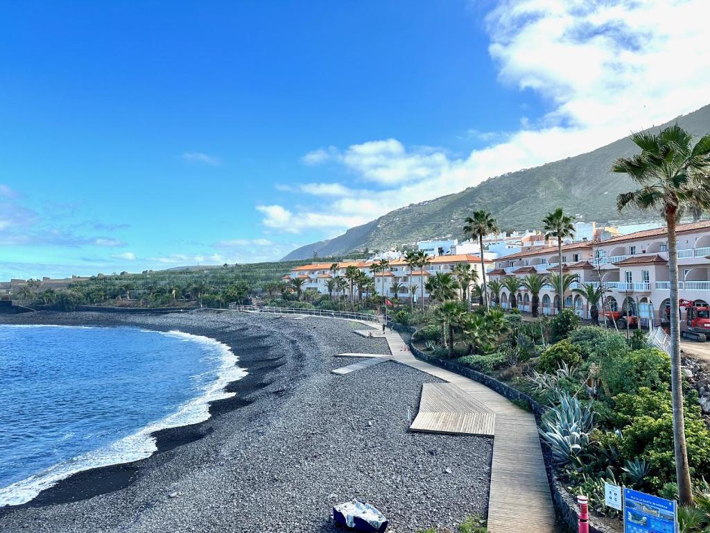 a beach with palm trees and buildings and the ocean at Casa Estrada Coastal Haven in Caleta de Interián