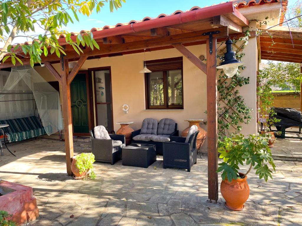 eine Terrasse mit Sofas und Stühlen unter einer Pergola in der Unterkunft Your Home in Argalasti in Argalasti